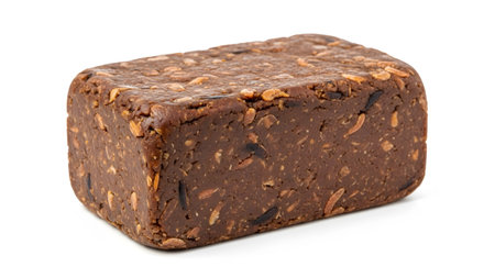 A rectangular block of dark brown fermented soybean paste with visible grains and seeds sits on...