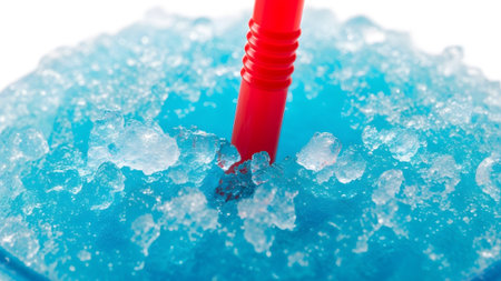 A vibrant blue slushy drink fills a glass, topped with crushed ice and a bright red straw.