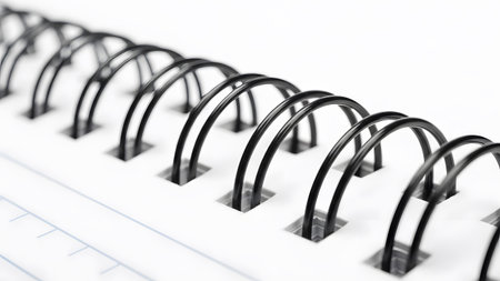 A close-up perspective of a black spiral binding securing white perforated pages of a notebook.