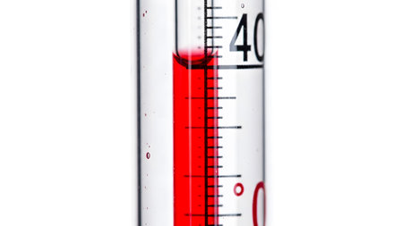 Scale showing close up of a thermometer with red liquid and temperature scale against a white...