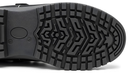 A close-up of a dark grey boot sole reveals a detailed geometric tread pattern designed for...の写真素材