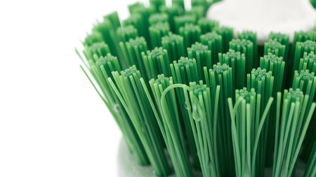 Bristles showing close up of green cleaning brush bristles with water droplets on white...