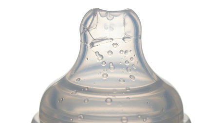 Background showing close up of a clear silicone baby bottle nipple with small water droplets and...