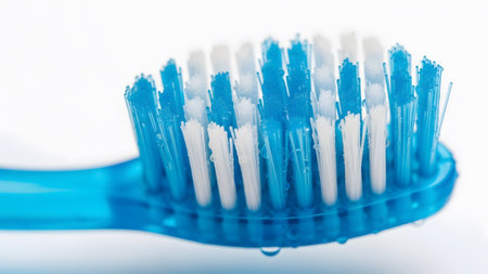 Stock showing close-up of a blue and white toothbrush with water droplets on bristles.