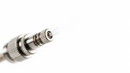 A detailed macro view of a silver metal connector with a knurled grip and a small central opening.