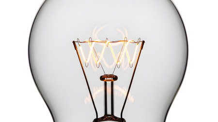 Detailed close-up of a glowing incandescent light bulb filament emitting warm yellow light...