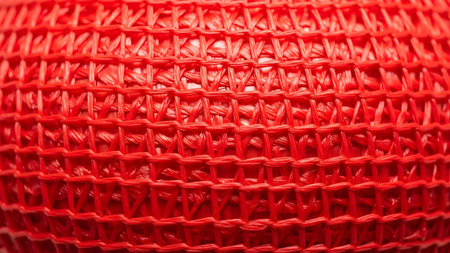 Pattern showing intricate red woven plastic mesh netting texture with repeating diamond pattern....の写真素材