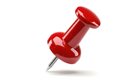 A single shiny red push pin with a silver metal point is angled and isolated against a clean...