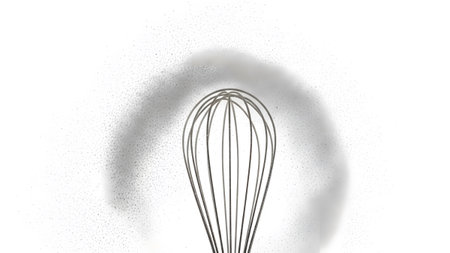 Stock showing view of a metal whisk with a shadow and dust particles on a white background.の写真素材