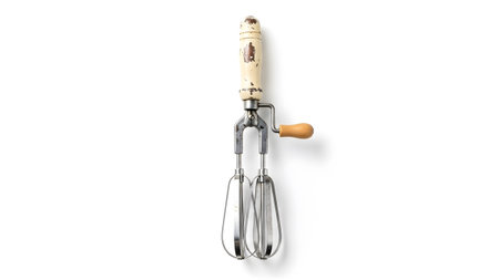 Wooden showing vintage hand crank egg beater with wooden handle and metal whisk attachments on...