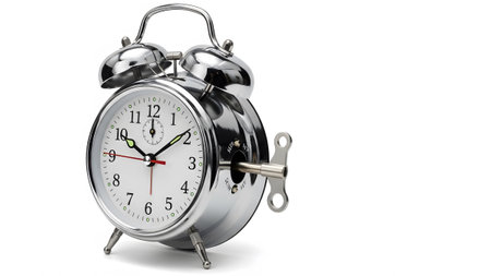 Background showing vintage twin bell alarm clock with winding key on white background isolated....