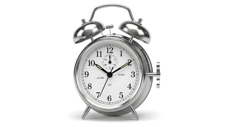 A shiny silver twin bell alarm clock with a white face the time and a set knob....