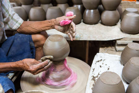 dirty hands making pottery in clay on wheelの写真素材