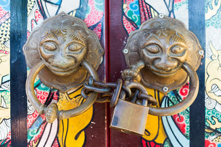 Old Chinese style door with iron chain and mythical wild animal head door handles.の写真素材