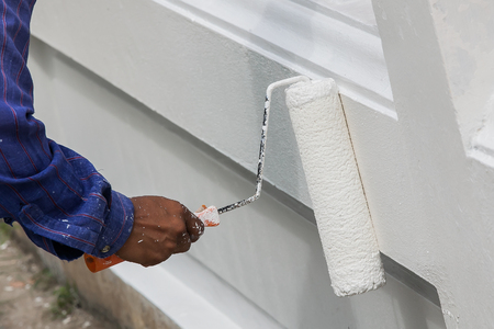 Close up of painter hand in white glove painting a wall with paint rollerの写真素材