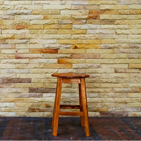 Vintage wooden chair with stone wall backgroundの写真素材
