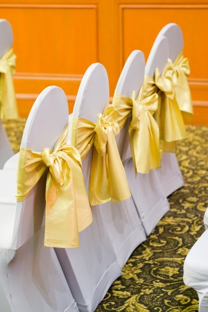 Row of white chairs decorated with gold ribbonsの写真素材
