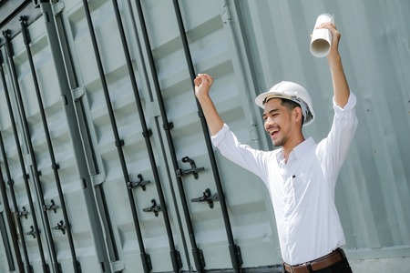 Full of energy. Pleasant emotional handsome architect rising his hands and smiling while evincing happinessの写真素材