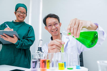 Male scientist standing with techer in lab worker making medical research in modern laboratory. Scientist holding documents folder with analysis results.の写真素材
