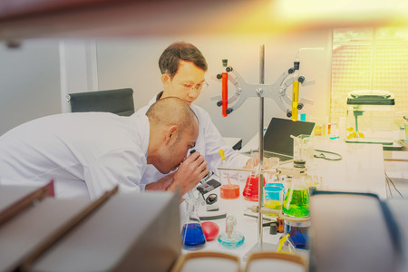 Male scientist standing with techer in lab worker making medical research in modern laboratory. Scientist holding documents folder with analysis results.の写真素材
