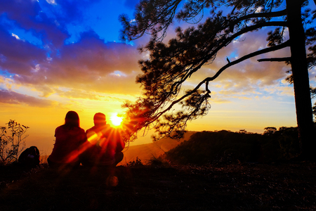 Silhouette of happy young couple in love looking view sunset on the mountain. Romantic couple in loveの写真素材