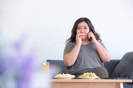 Fat Asian women are enjoying eating French fries in the room.の写真素材