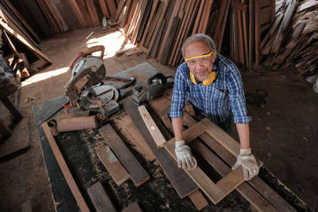 The male carpenter uses sandpaper to polish the woodwork.の写真素材