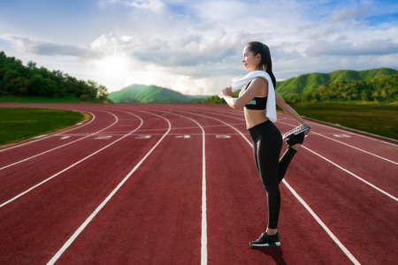 Beautiful young athletes warm up before running practice in an outdoor stadium.の写真素材