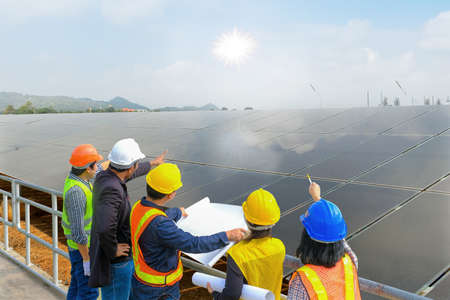 A man and a woman, an engineer and a supervisor, reading the blueprints at the construction site. Solar cells are electric power.の写真素材