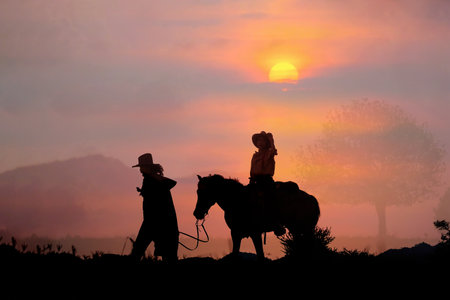 The silhouette of the cowboy and the setting sunの写真素材