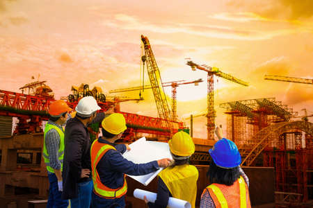Men and woman meeting with Engineers and supervisors are standing reading the blueprints at the construction site.の写真素材