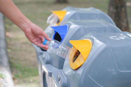 Hand holding plastic bottle and throwing into the garbage for recycle.の写真素材