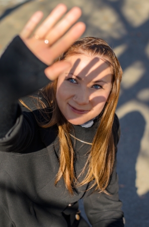 Long-haired, pretty girl in a coat closed by hand from the sun.の写真素材