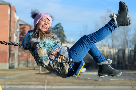 Cheerful little girl playing on a swing.の写真素材