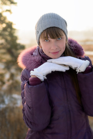 Charming young girl in gloves, in the light of sunset.