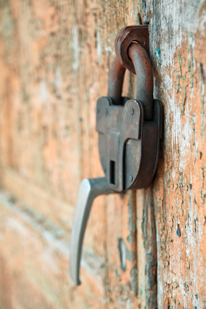 Ancient door with a padlock. Grunge paint on wood upholstered. Protection of abandoned estatesの写真素材