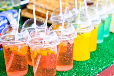 Cold drinks of juice and alcohol in a plastic cup with a tube. Summer holidays and food in nature. Stock Photoの写真素材