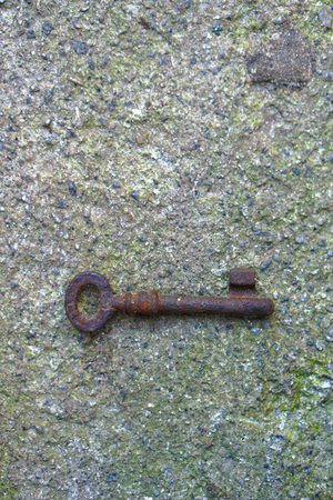 An antique rusty metal key on the background of concrete. A romantic secret protected by mystery. Stock photo.の写真素材