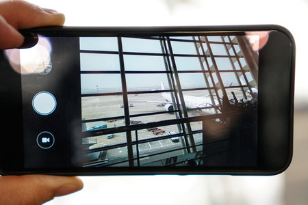 Phone in the hands of a tourist photographing the plane at the airport.