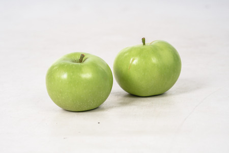 Two lovely green juicy apples on a white isolated background. Vegetarian food.の写真素材