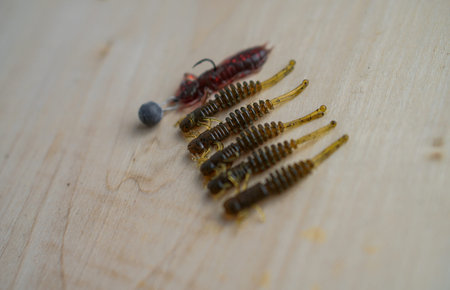 Colorful silicone fishing baits with plummets on wooden table. Various fish and worms and crayfish....