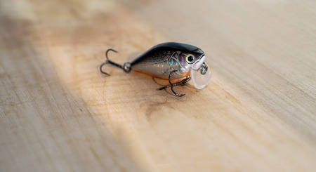 Colorful fishing baits with plummets on wooden table. Wobbler on a wooden board with beautiful eyes. Toned image and top view. Stock background, photoの写真素材