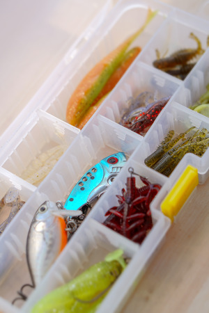 Colorful silicone fishing baits with plummets on wooden table. Various fish and worms and crayfish. Toned image and top view. Stock background, photoの写真素材
