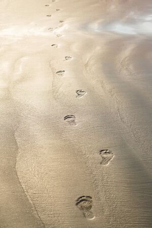 Footprints of bare feet on the sand of the beach. The coast of the ocean, the sea. Tourist background for travel agency. Stock photoの写真素材