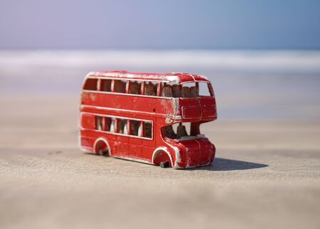 Red toy bus in nature pollutes the earth's ecosystem. English bus without wheels. Consumer world without environmental concernsの写真素材
