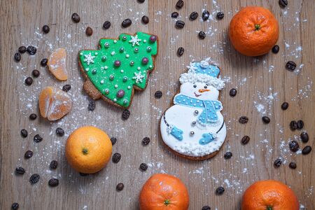 Beautiful gingerbread cookie in the form of a snowman and a Christmas tree on a background of a wooden texture with coffee grains. Winter christmas themeの写真素材