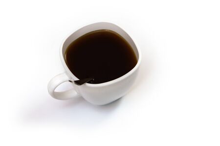 White cup of coffee with a spoon on an isolated background. Black cappuccino drink in a bowlの写真素材