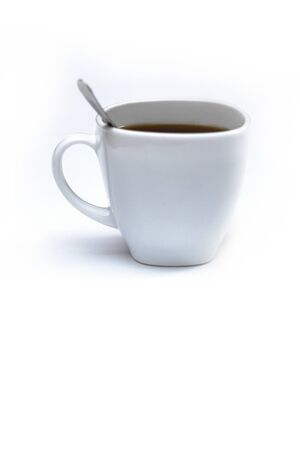 White cup of coffee with a spoon on an isolated background. Black cappuccino drink in a bowlの写真素材