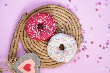 Beautiful juicy donuts with sweet in plates on a decorative tray. Cupcake on a pink background with colorful hearts for kitchen designの写真素材