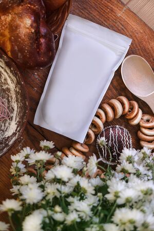 Template of paper ecological bag for storing coffee, tea on a wooden kitchen table with sweets. making donuts and croissants for the holidayの写真素材